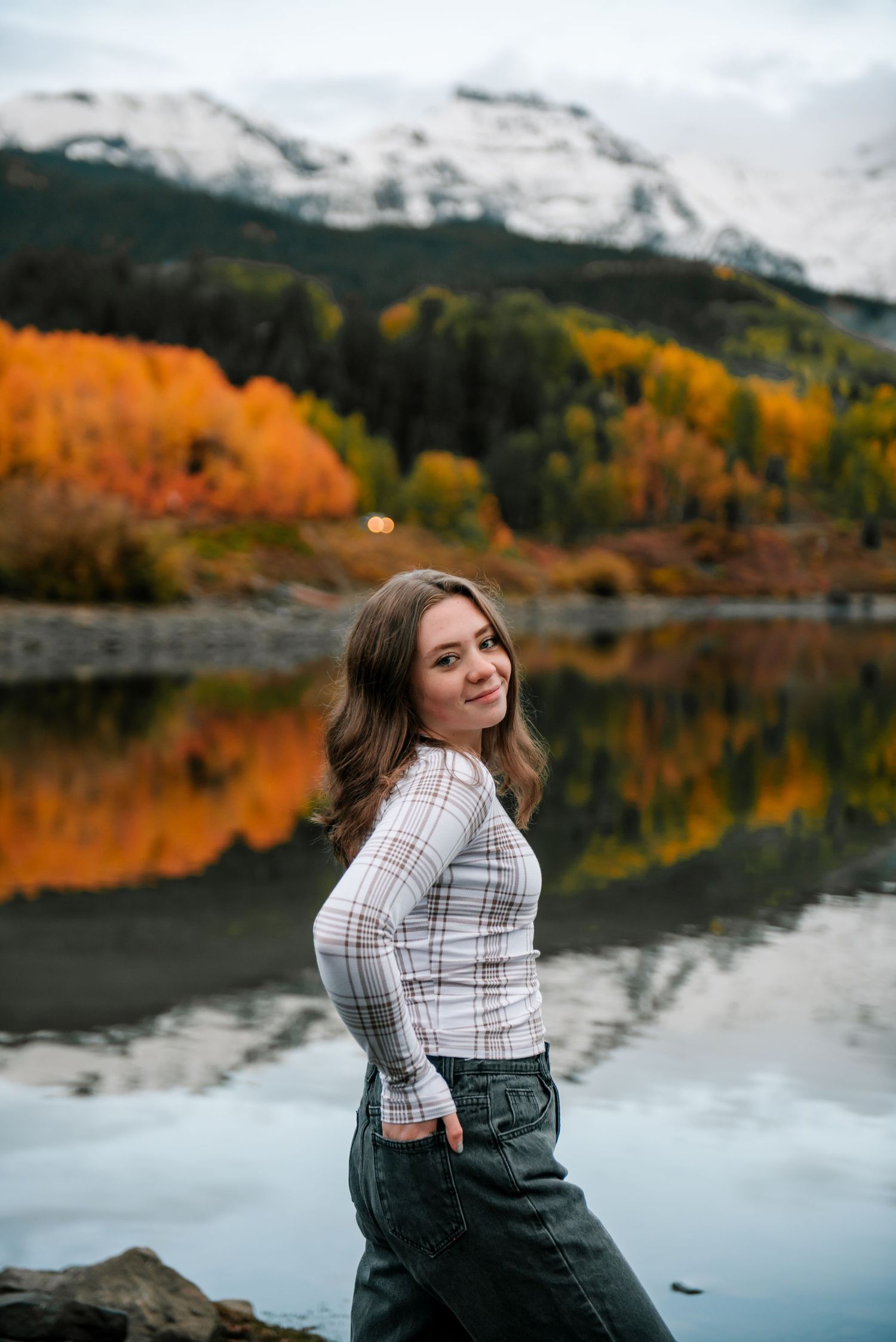 Scenic autumn landscape with snow-capped mountains and golden foliage reflecting in a calm mountain lake.
