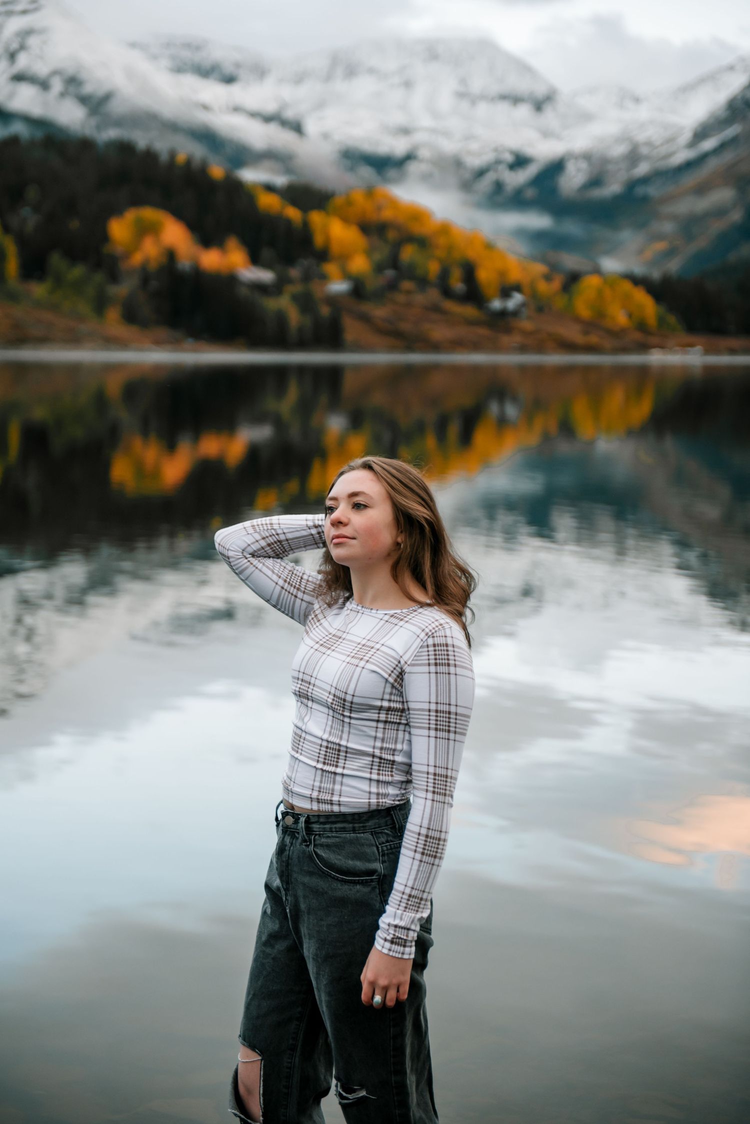 Dramatic mountain scenery with fall colors and snowy peaks mirrored in still waters during autumn.