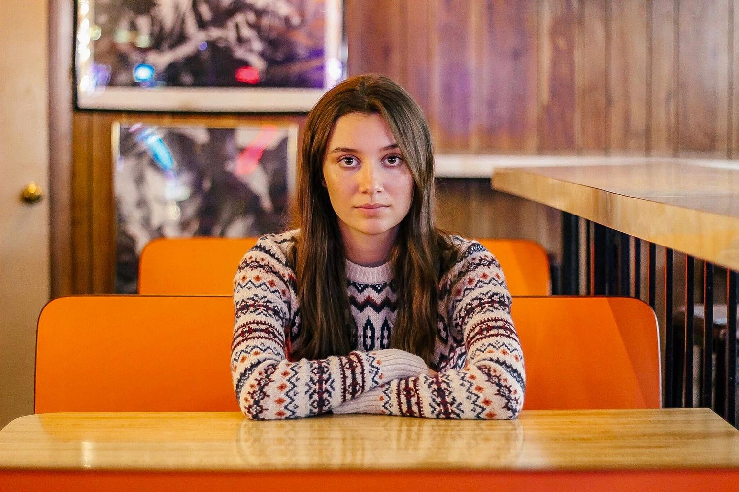Girl in striped sweater sitting in orange retro inspired booth
