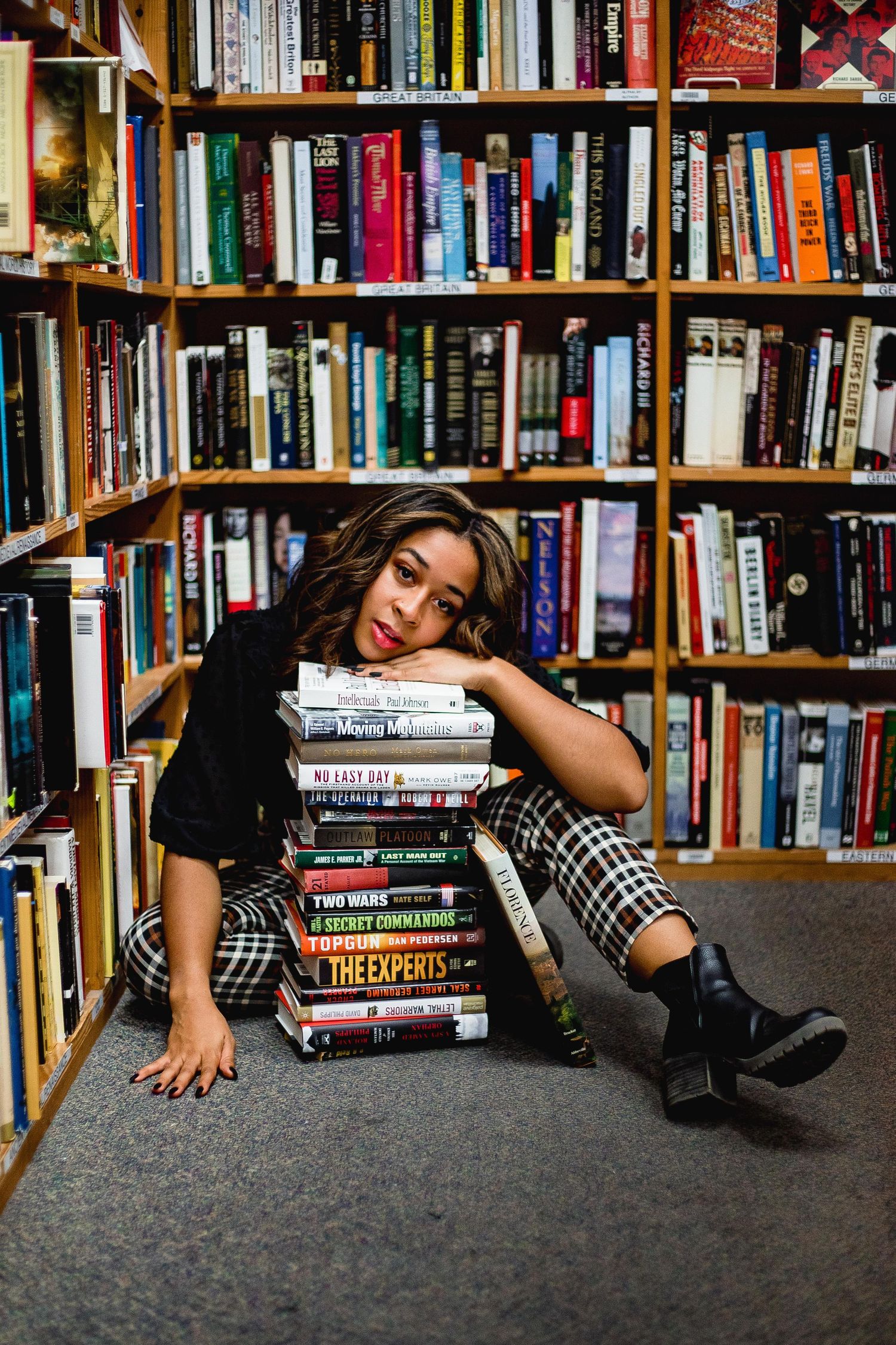 Girl leaning her head on a stack of books at a book store