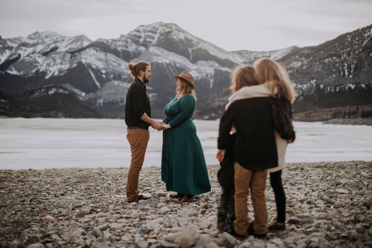People gathered by a mountain lake with snow-capped peaks in the background.