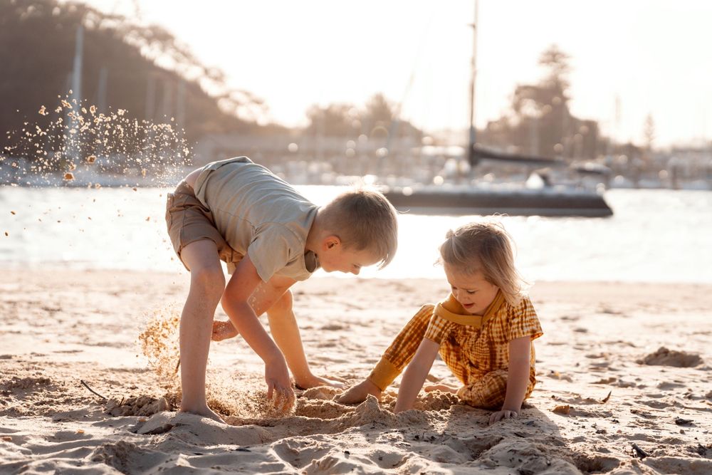 boy siblings playing in the sand at Sydney during a family photoshoot