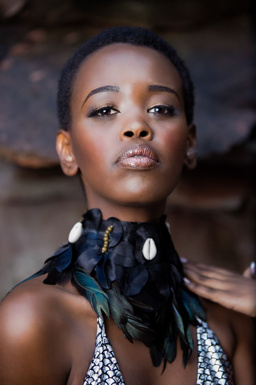 Close-up beauty shot with dramatic feather collar necklace and shimmering makeup.