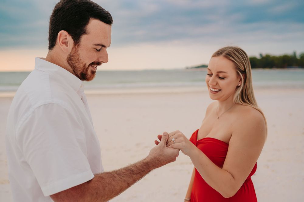Man holding woman's hand and looking at her engagement ring after just proposing.
