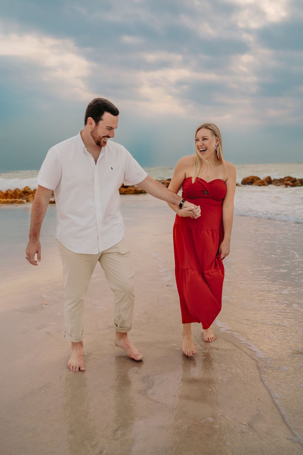 Man and woman walking hand in hand down the beach at sunset on Anna Maria Island.