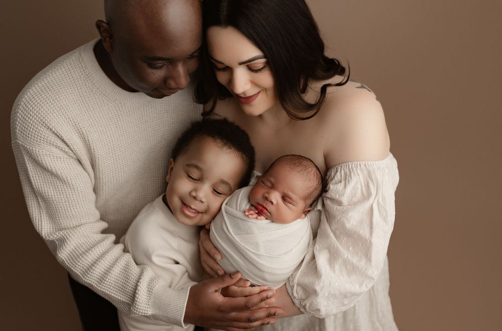 An emotional family portrait captured in warm brown tones showing tender embrace.