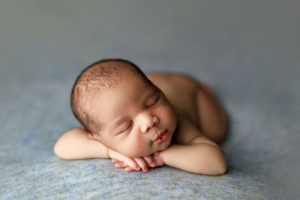 Peaceful newborn baby sleeping on soft blue textile in studio setting.