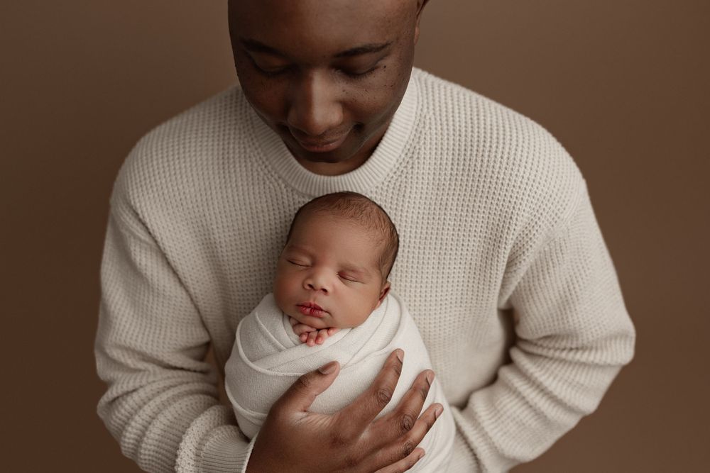 Tender moment between parent and newborn in cream colored knitwear.