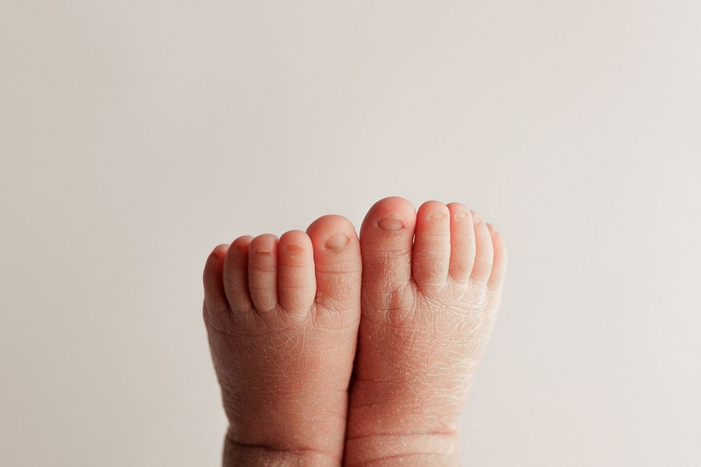 Close-up of two tiny newborn feet against white background.