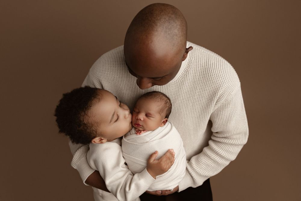 A tender family moment in warm sepia tones showing gentle embrace of a baby.
