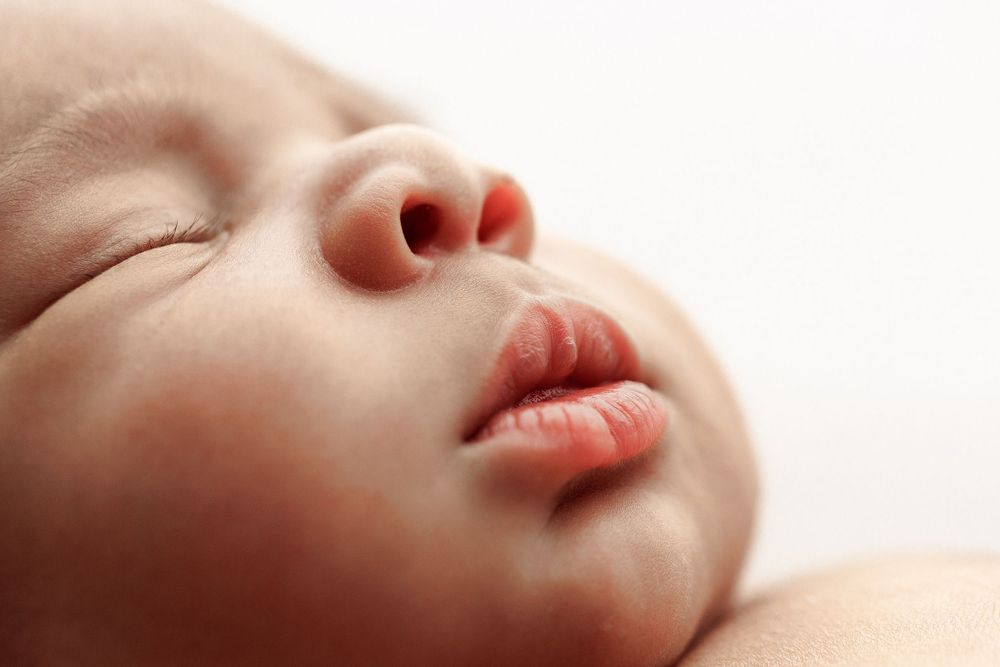 Close-up profile of sleeping newborn's face showing peaceful expression.