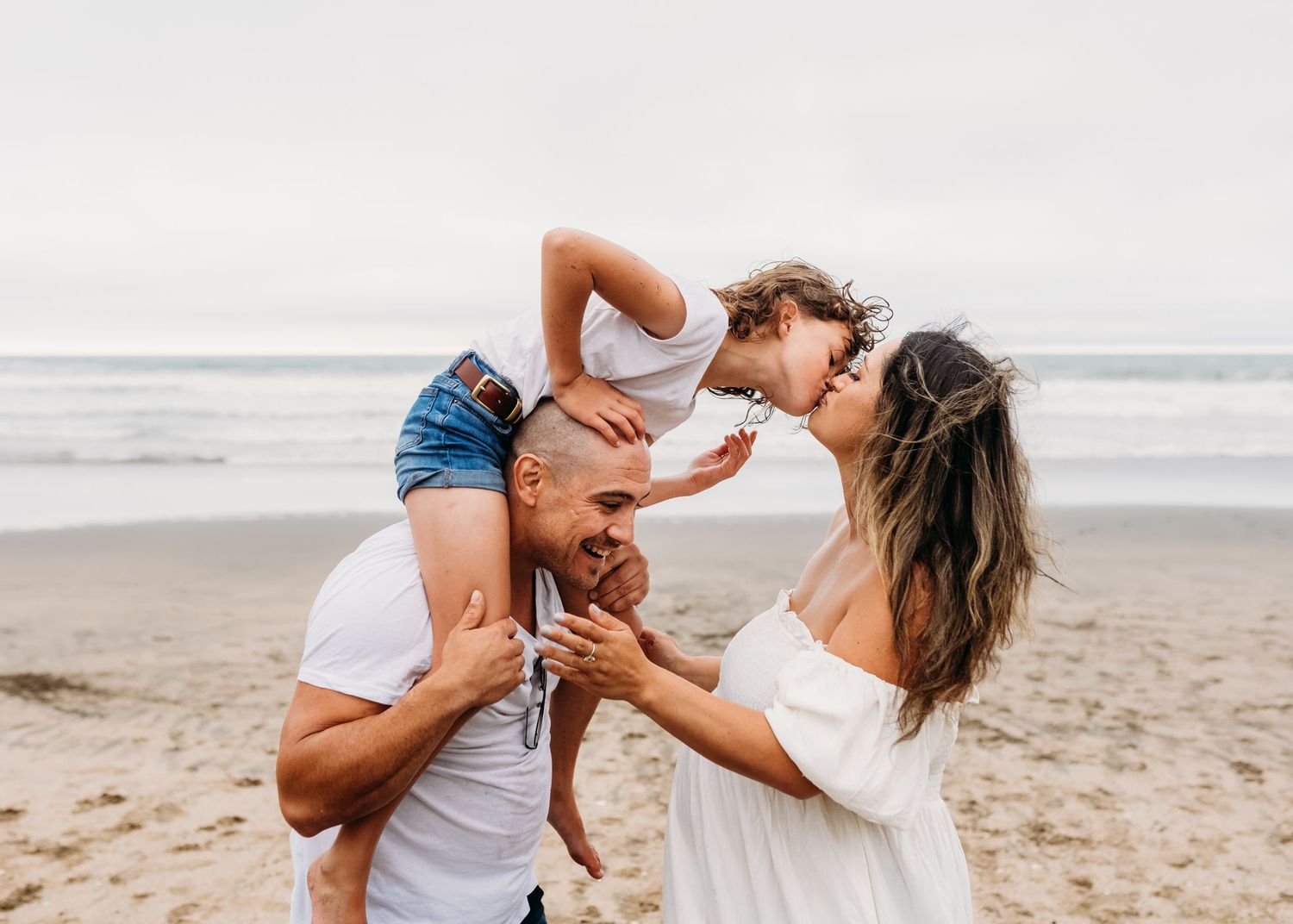 A happy family playing and laughing together on a sunny beach.