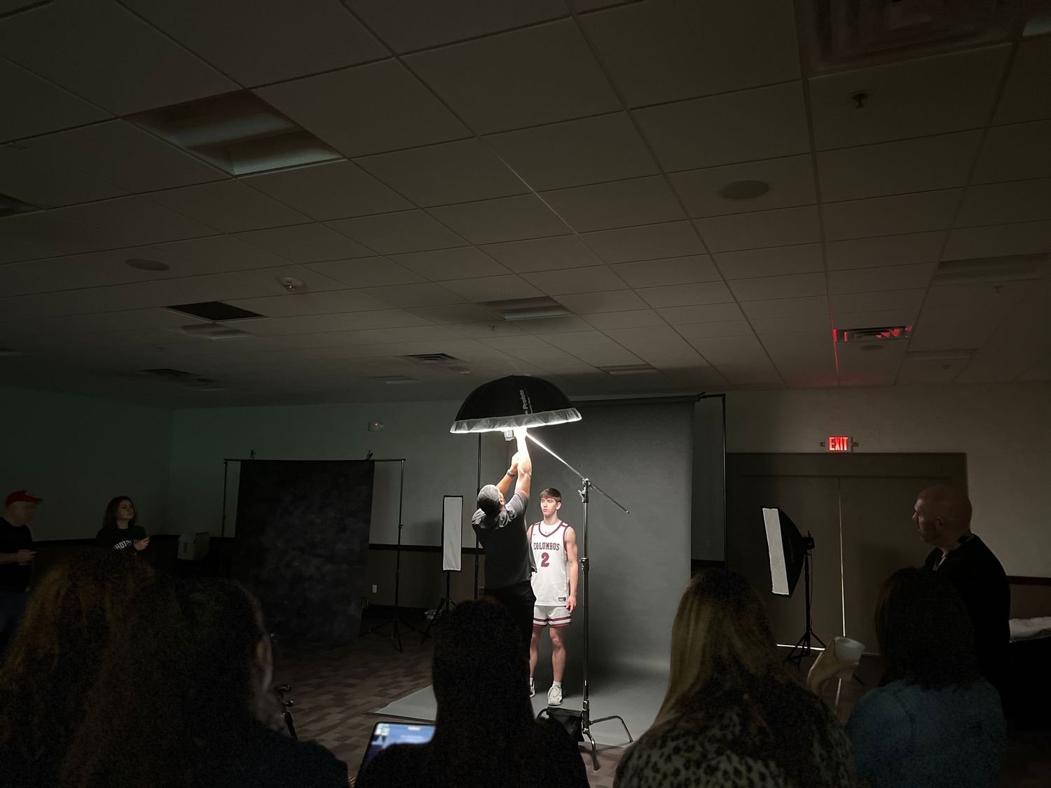 Dark indoor performance space with dramatic lighting and audience silhouettes.
