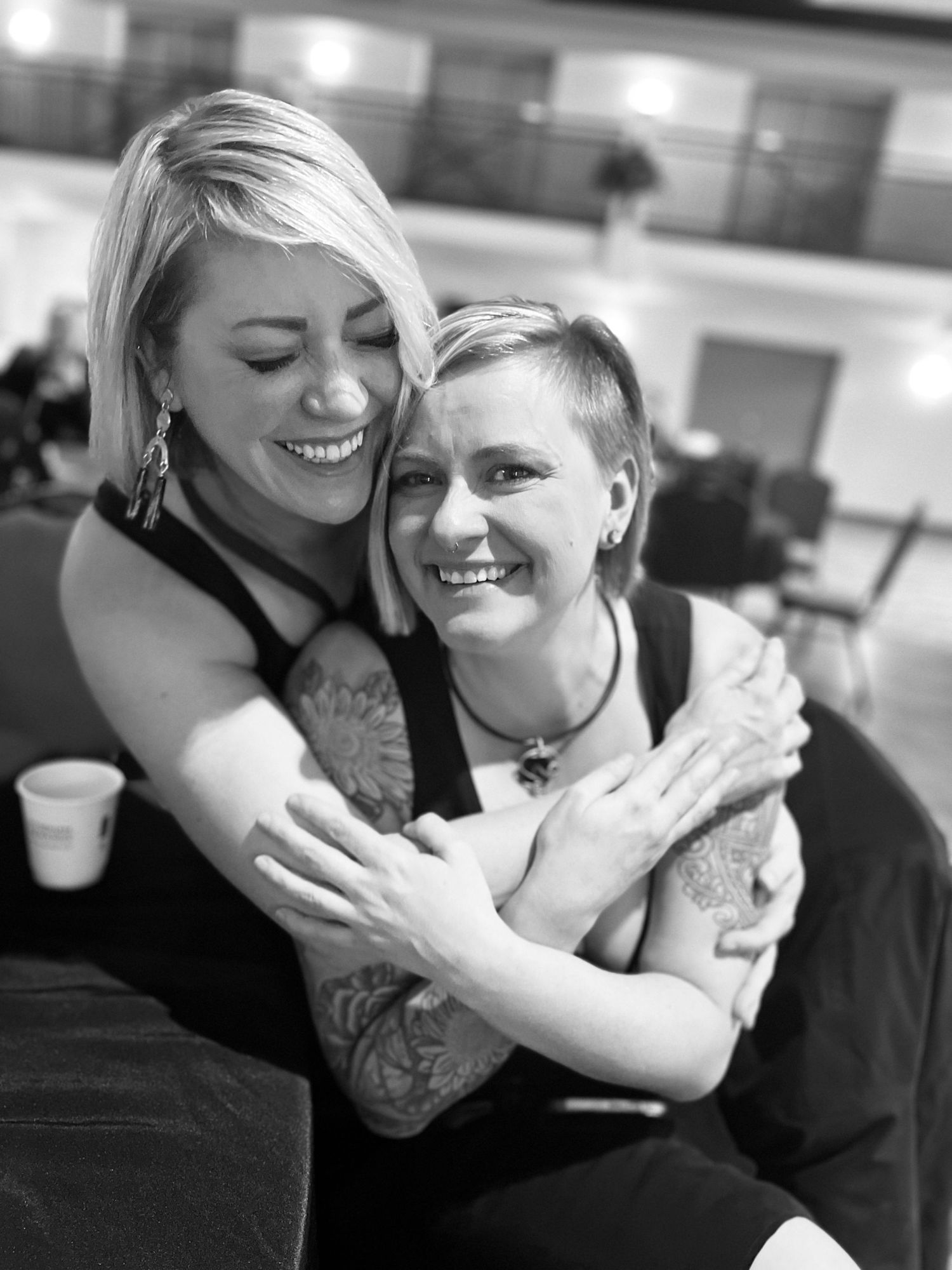 A black and white candid photo showing two people embracing and laughing.