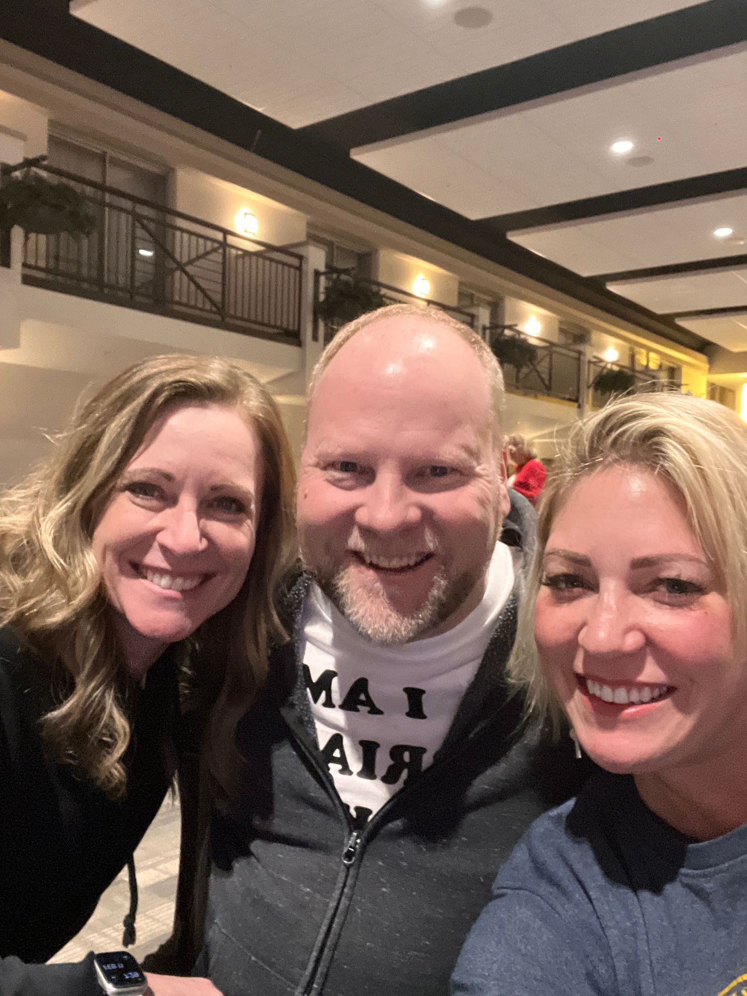Three people smile together for a casual indoor photo.
