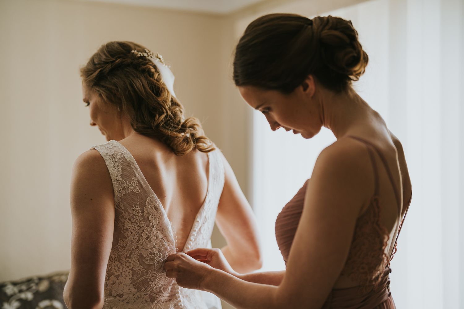 Sister helping Bride with her wedding dress