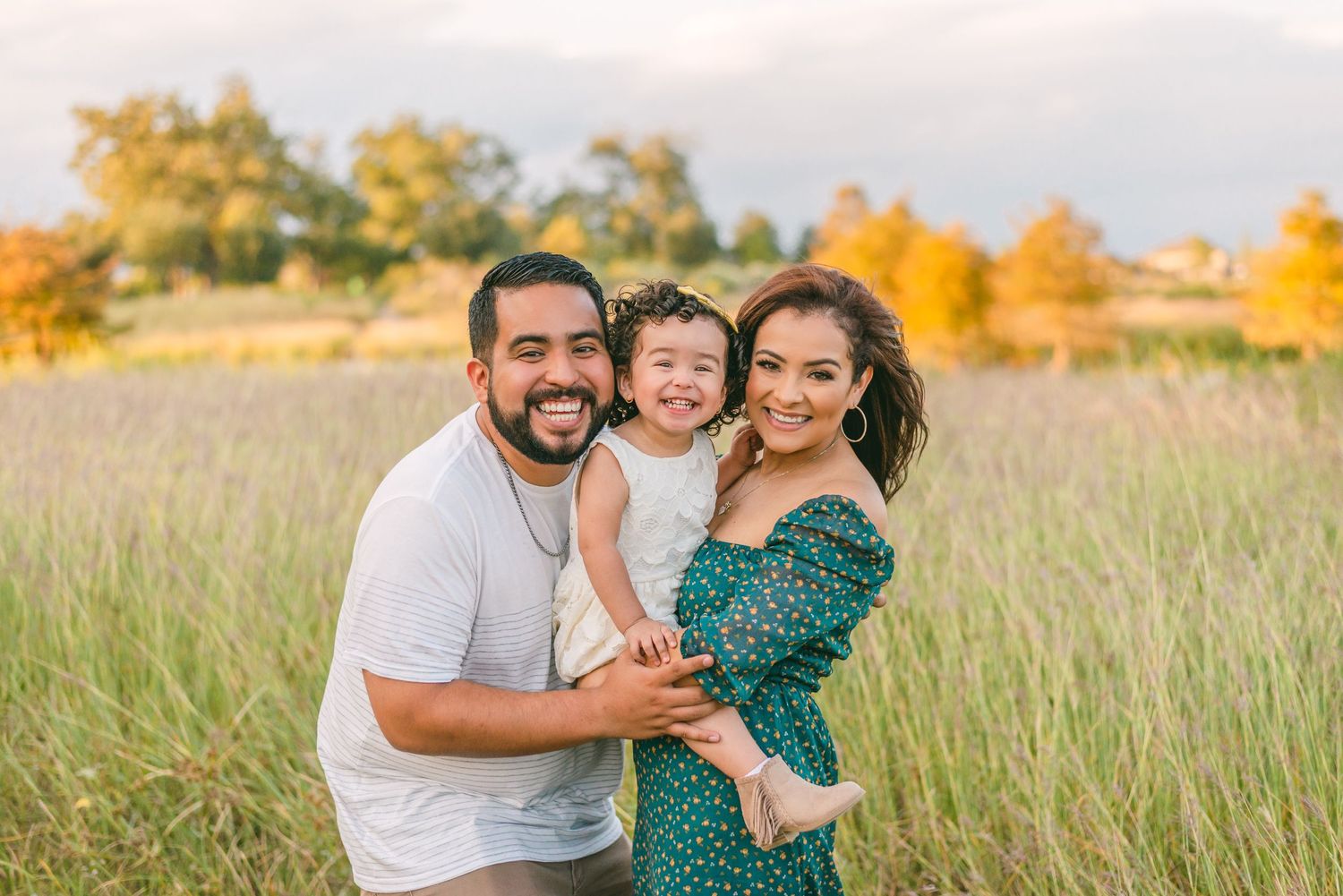 a family photo in a field of tall grass and golden trees