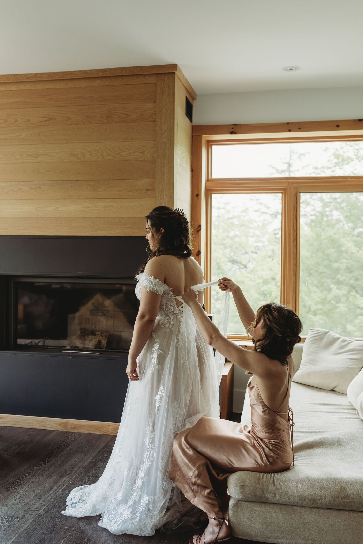 Wedding dress preparation scene in modern room with wooden finishes and large windows.
