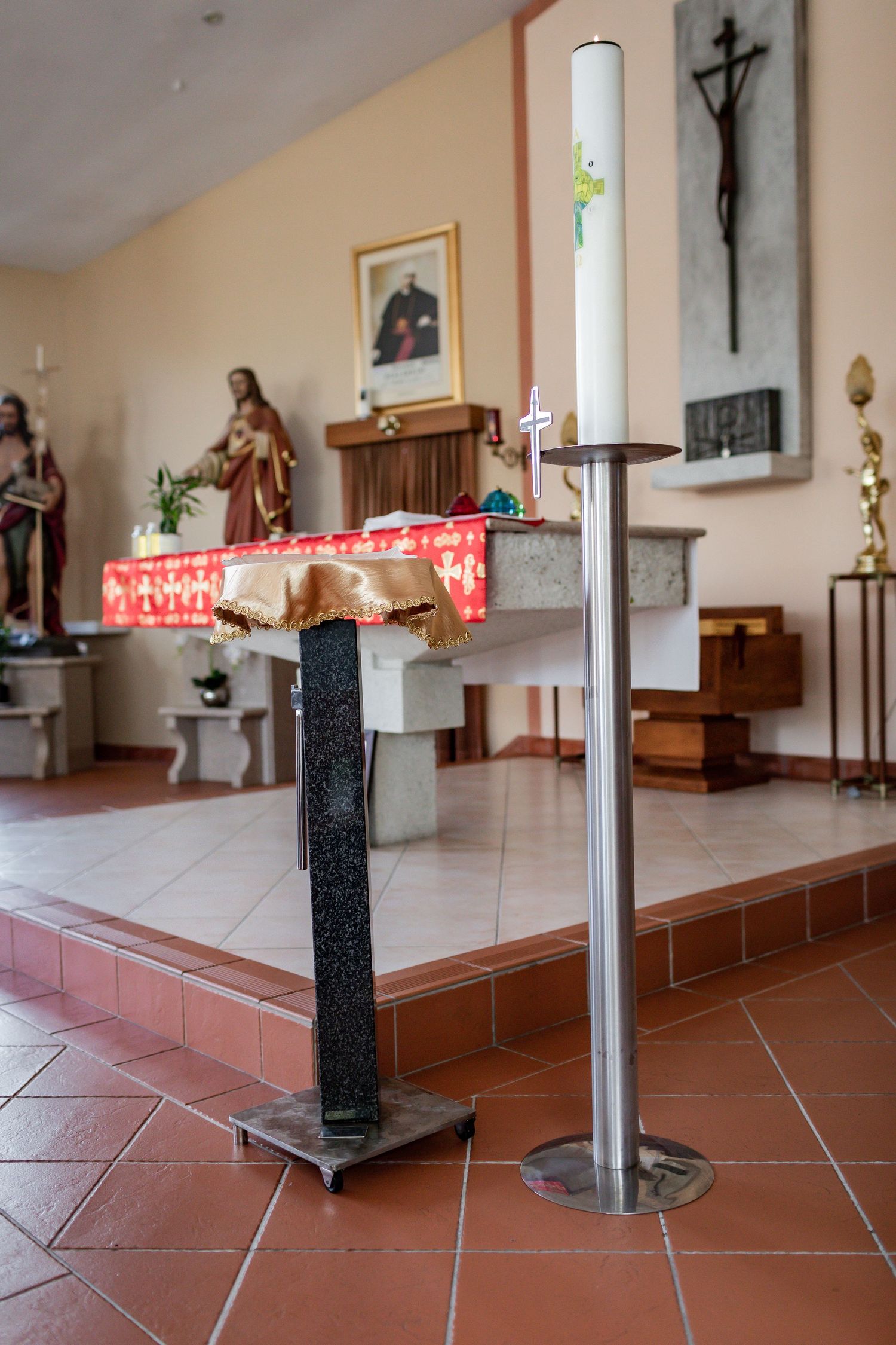 Close up of church altar showing candle holder, crucifix and religious statues.