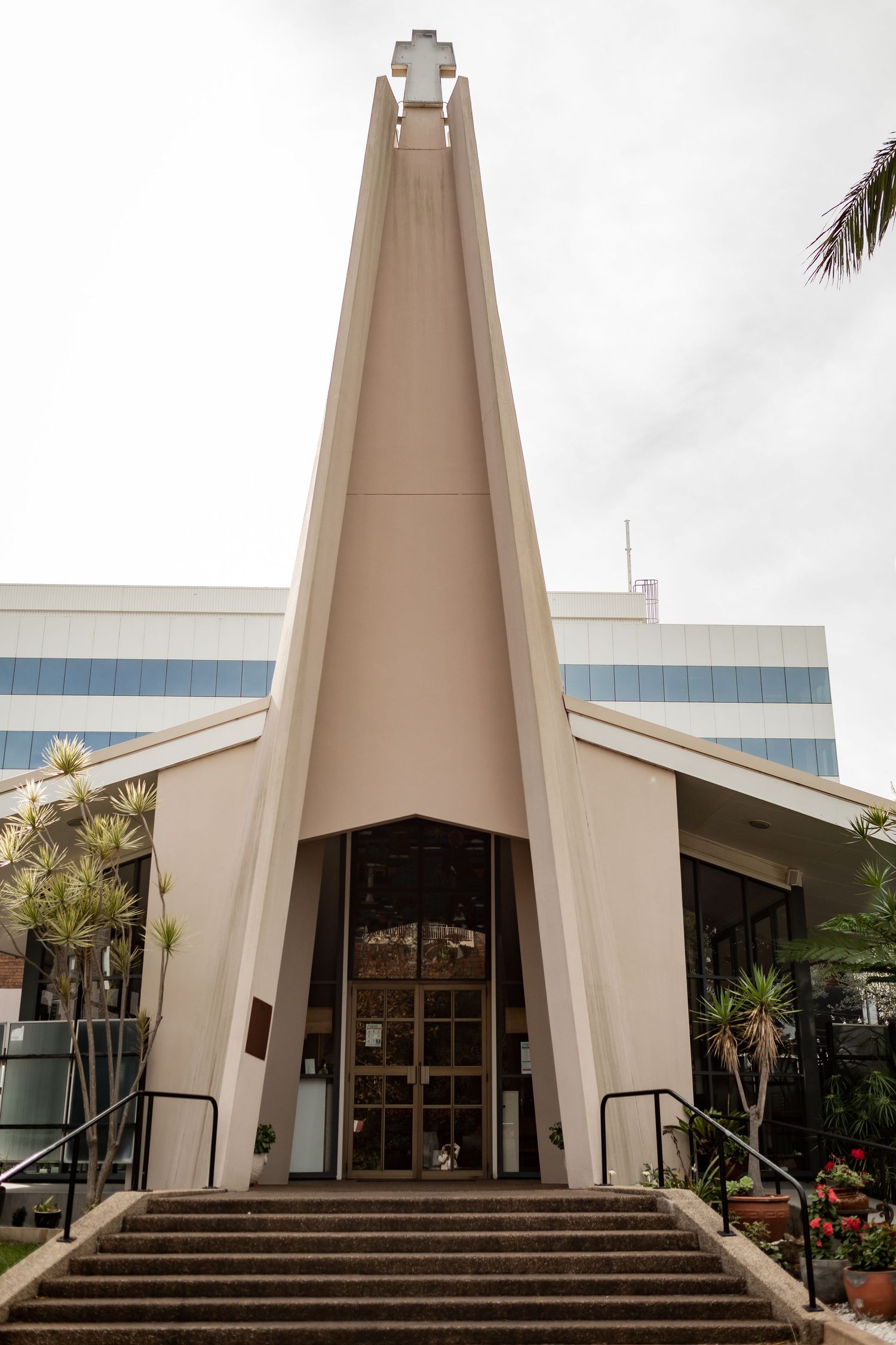 Modern church building exterior with dramatic pointed roof and glass entrance doors.