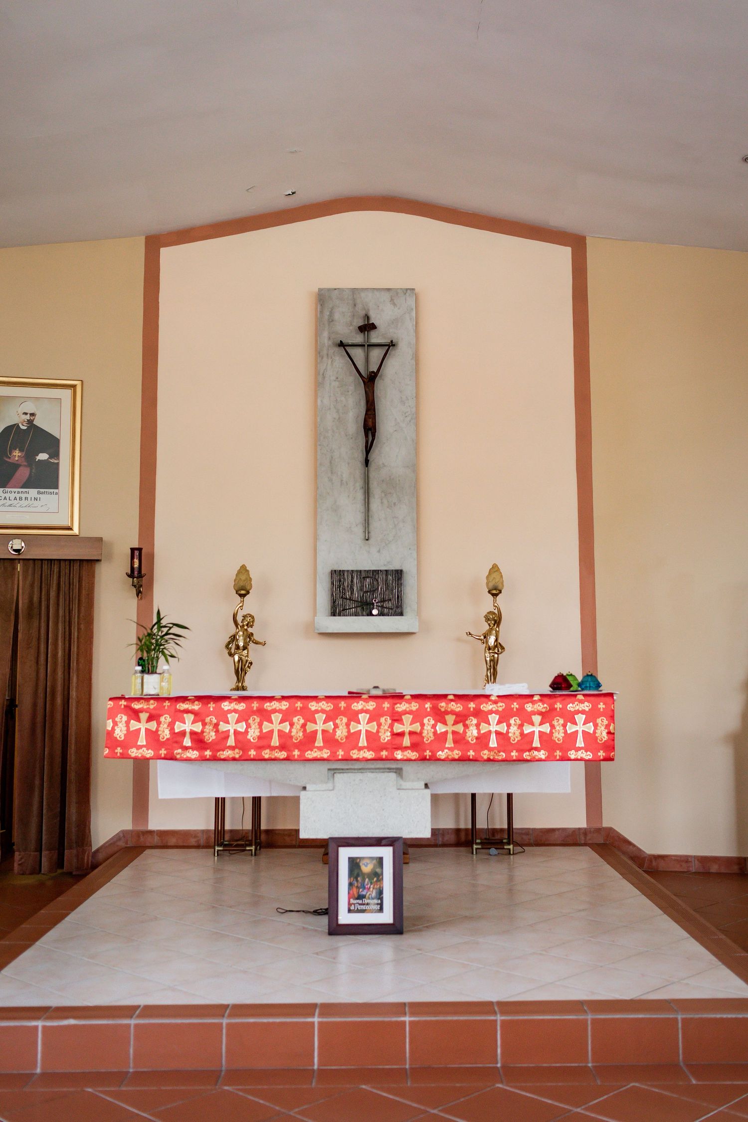 Church altar with crucifix, red tablecloth and religious decorations.