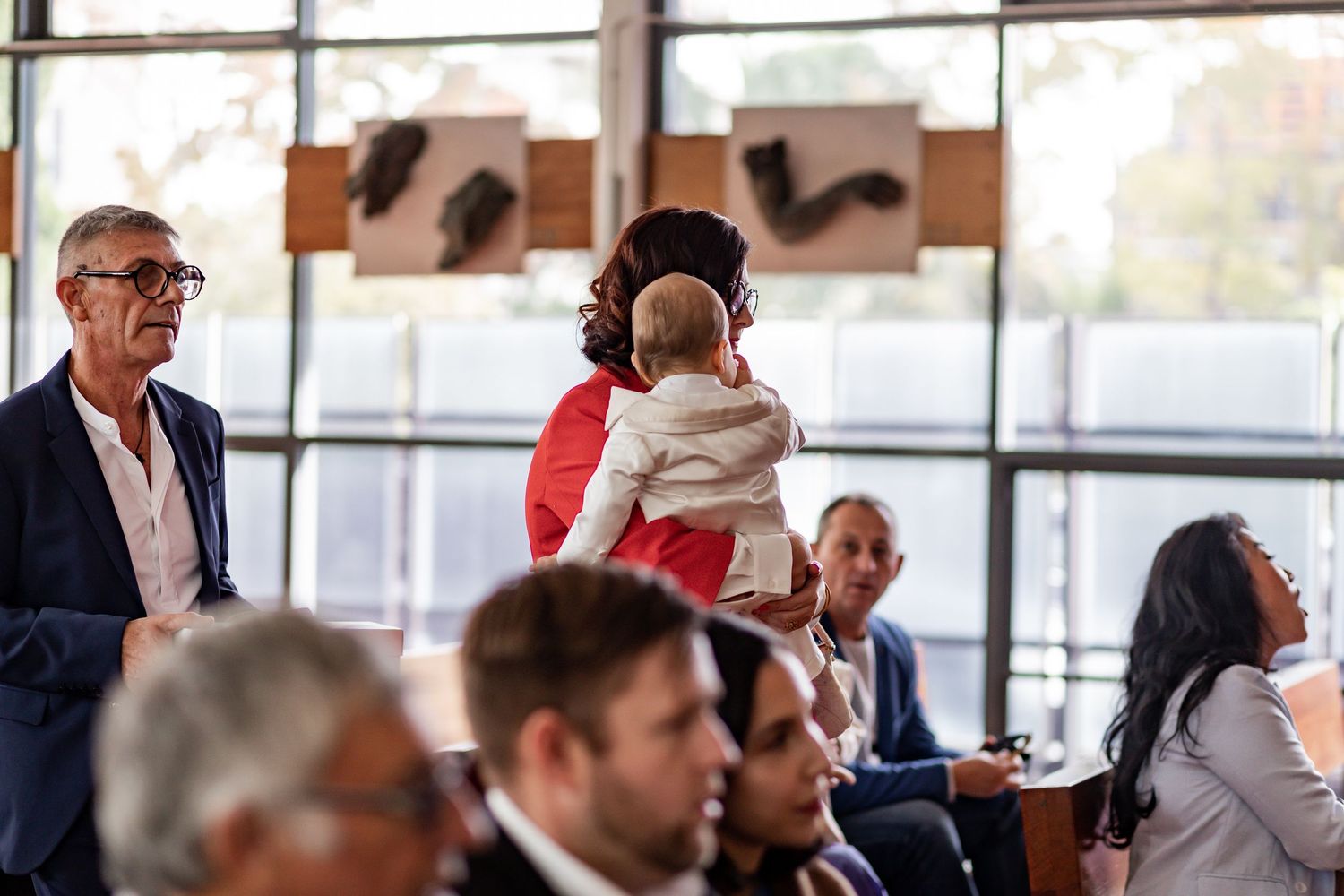People gathered in rows at an indoor event with natural lighting from windows.