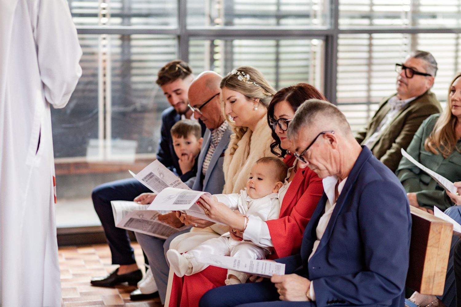 People sitting in pews during a religious ceremony while reading from booklets.