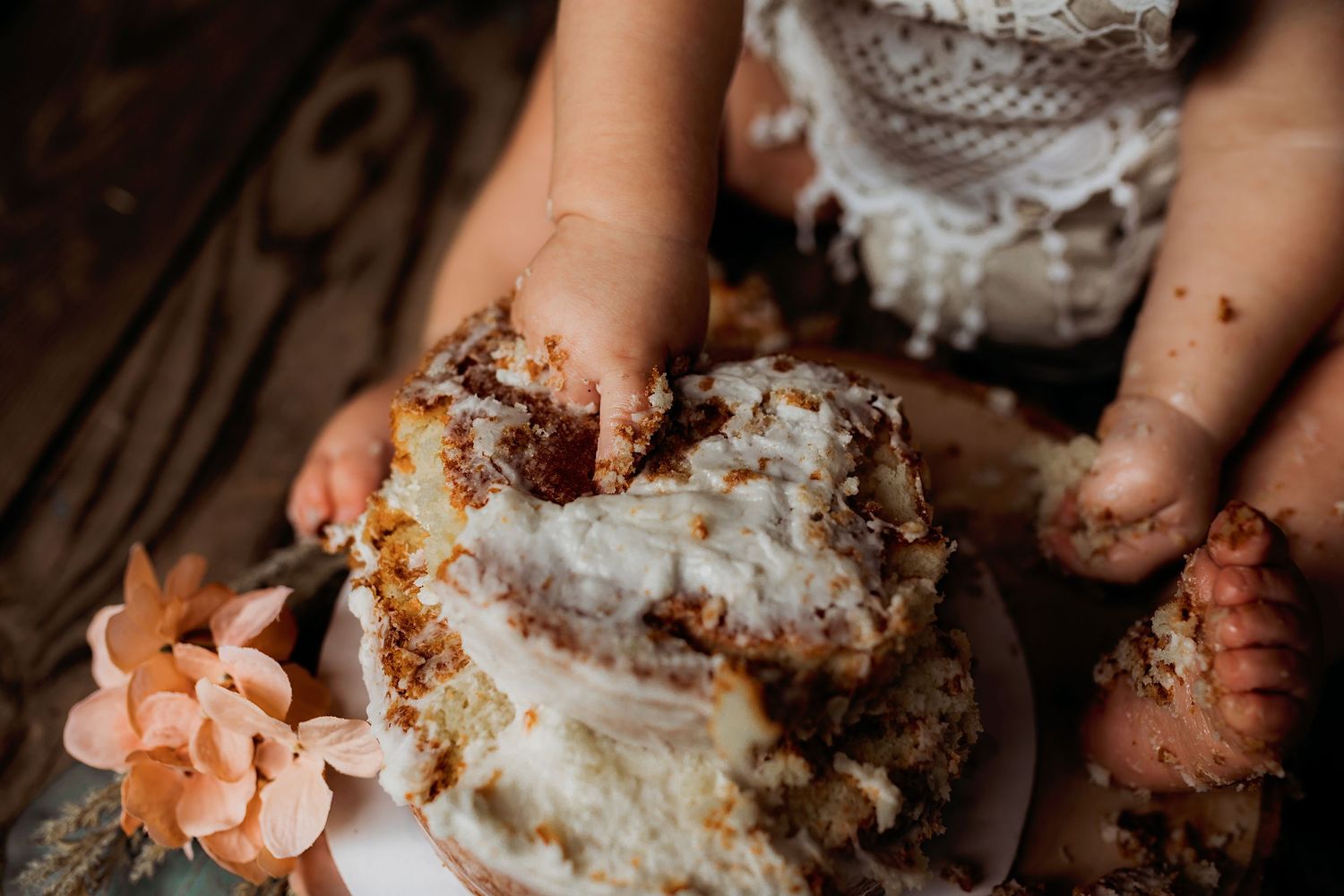 Close-up details of cake smashing and frosting during first birthday photoshoot.