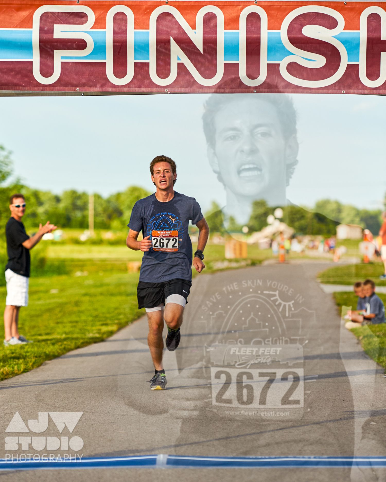 Runner approaching the finish line on a paved path during a race event.