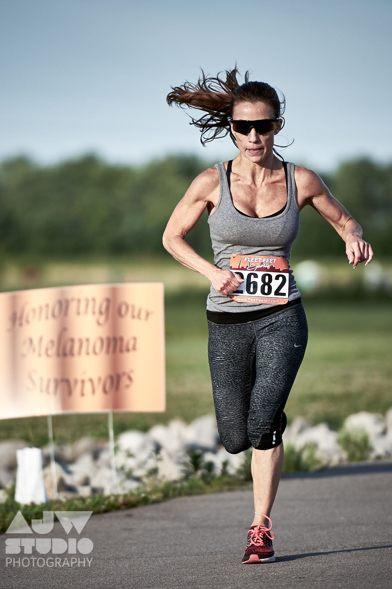 Athletic runner in motion during a melanoma awareness race on a paved path.