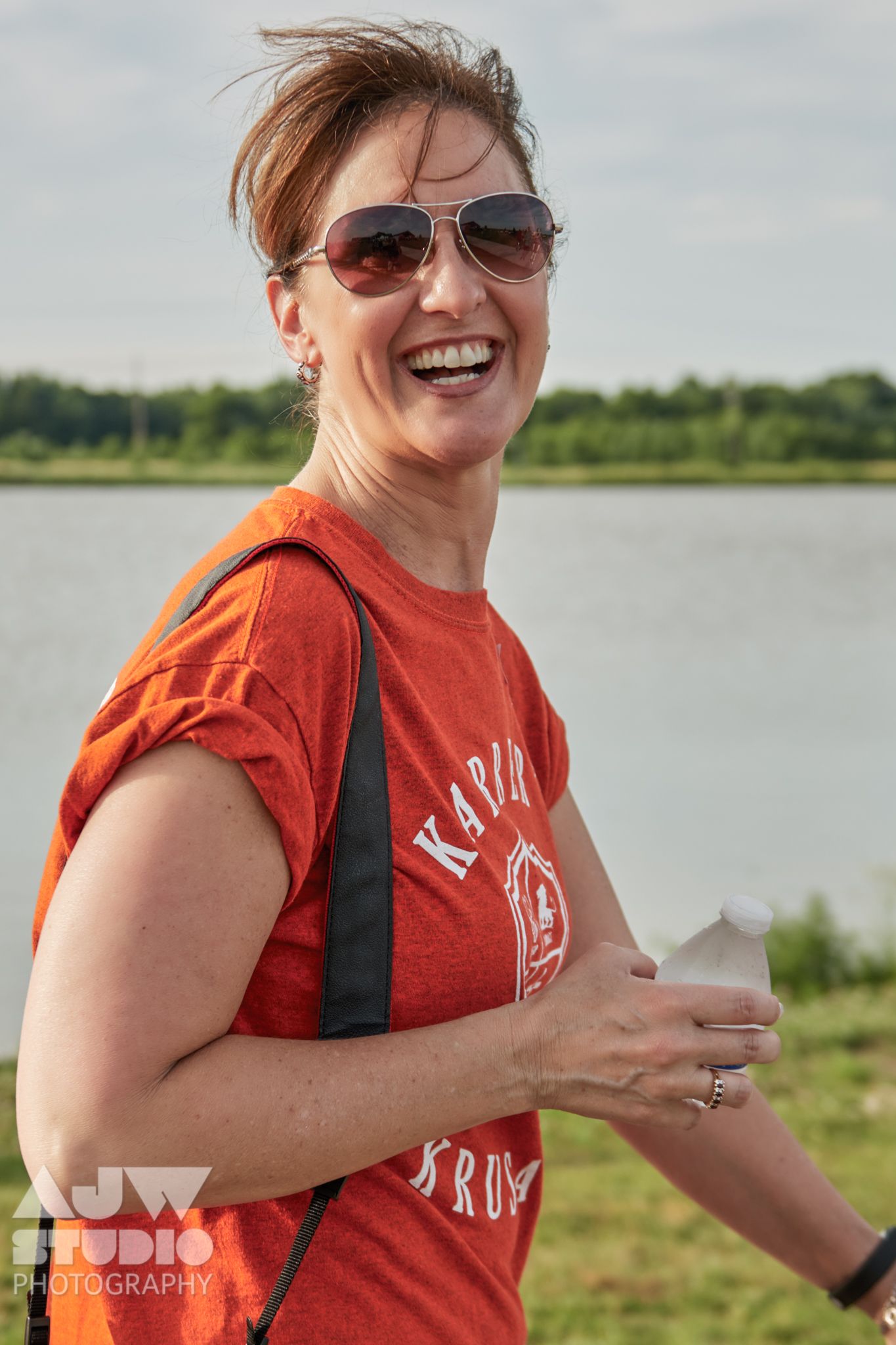Participant in orange shirt enjoying an outdoor event by a lake.