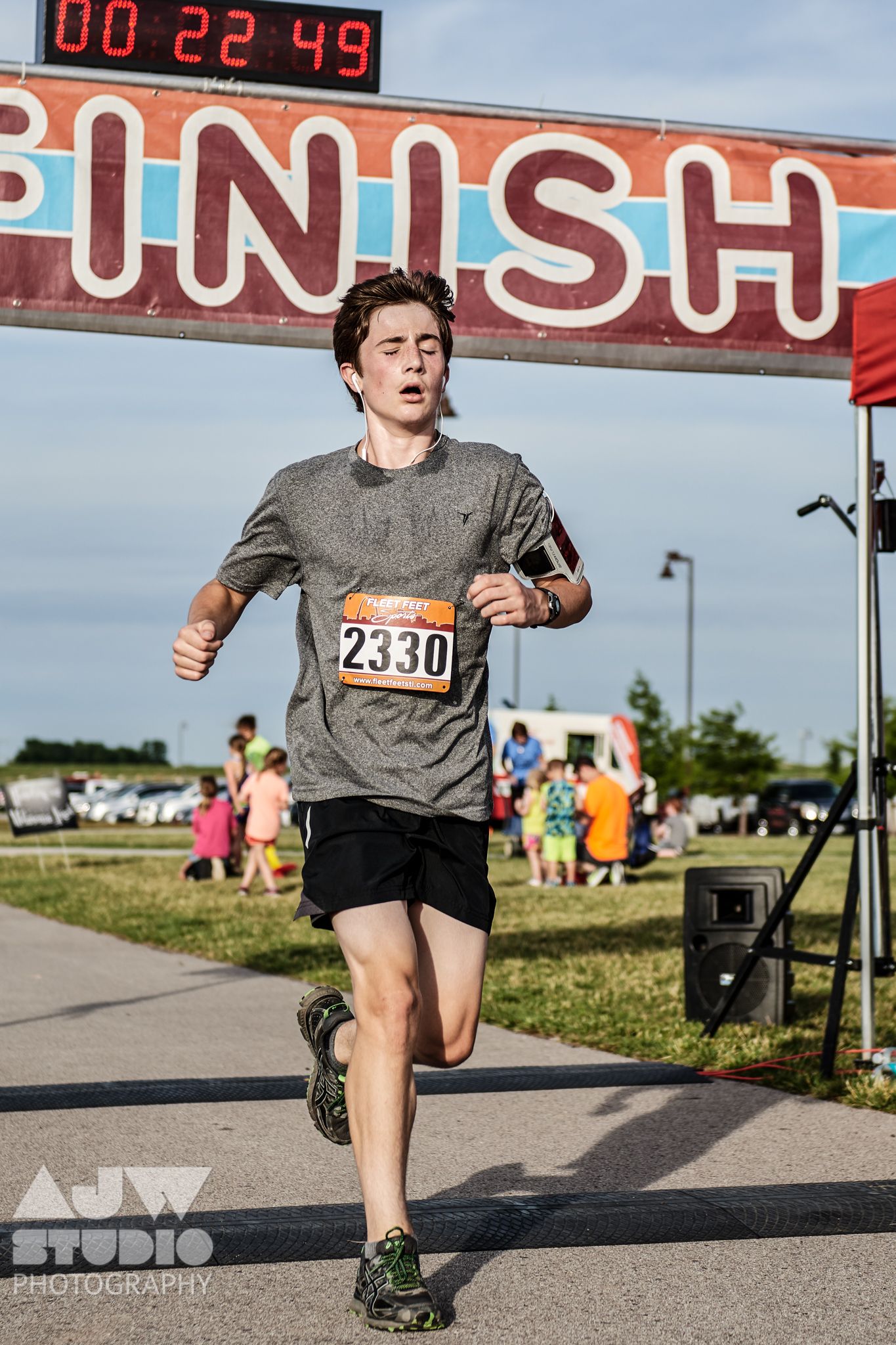 Runner crossing finish line with digital timer display showing elapsed time.