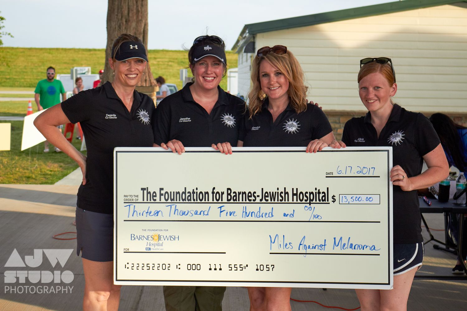 Group presents large ceremonial check for charity donation at outdoor event.