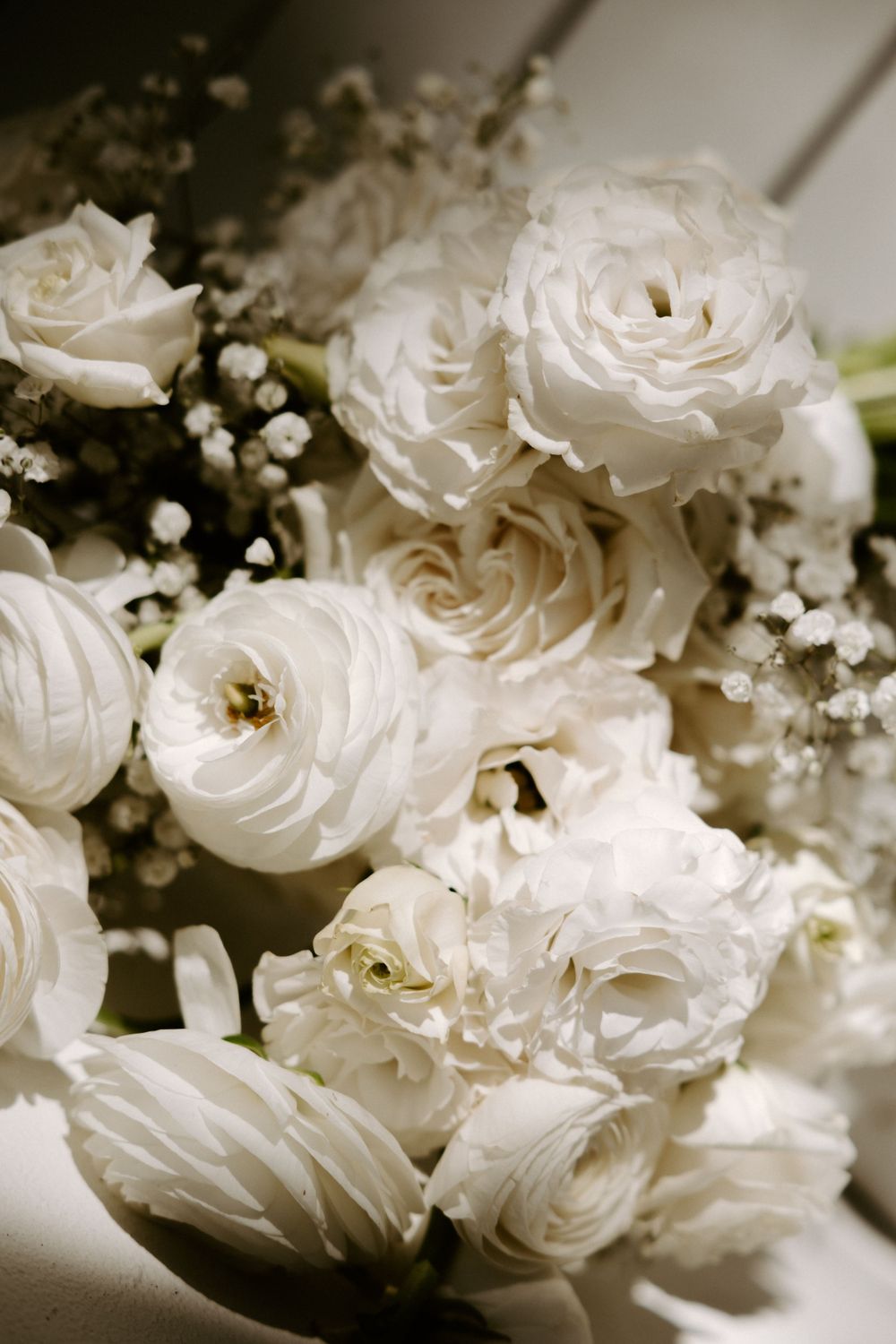 Close-up of elegant white roses and baby's breath arranged in a romantic wedding bouquet.