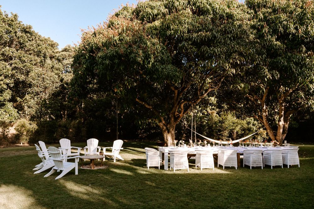 White Adirondack chairs arranged for an outdoor garden wedding ceremony.