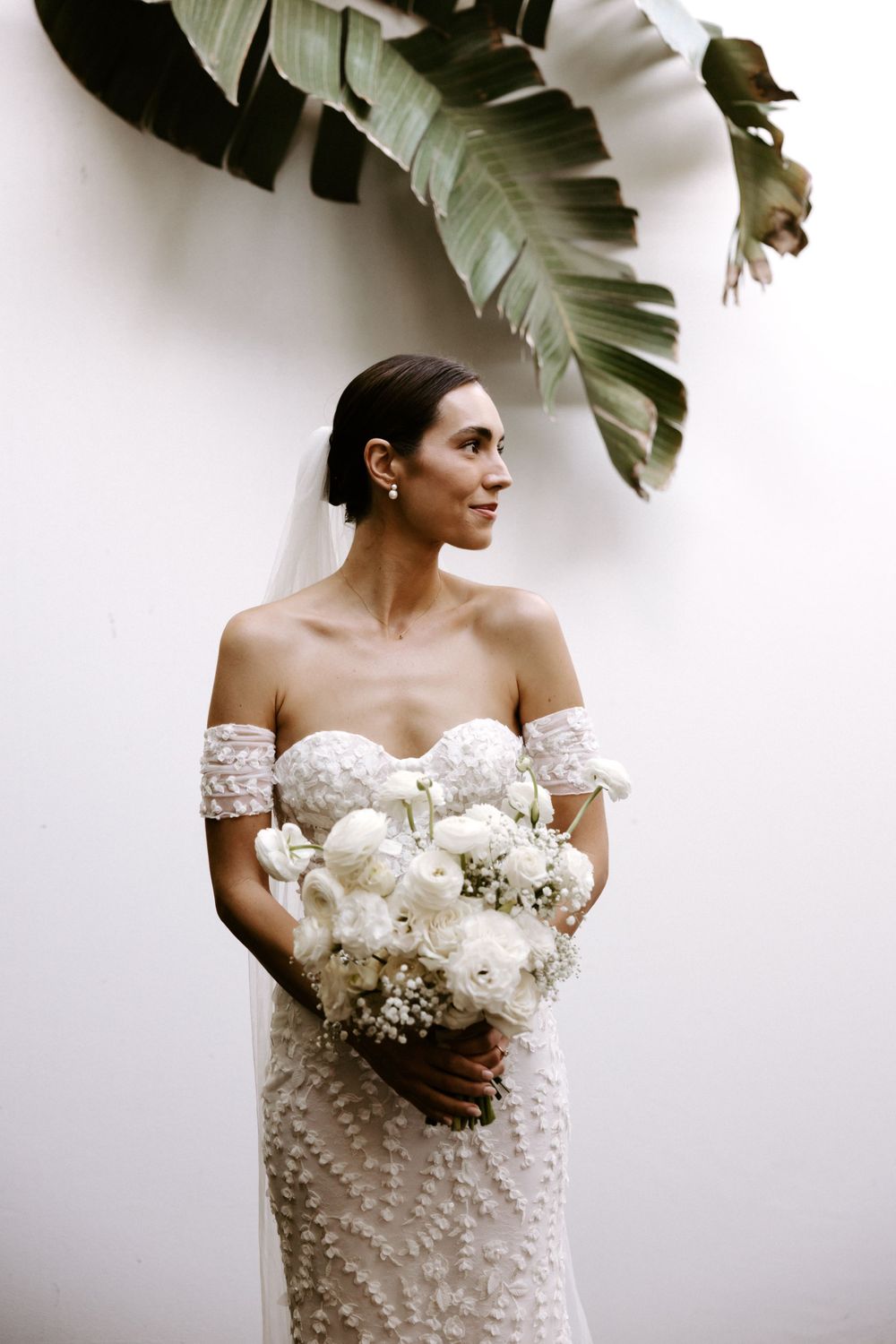 An elegant bridal portrait with a white bouquet against a minimal white backdrop.