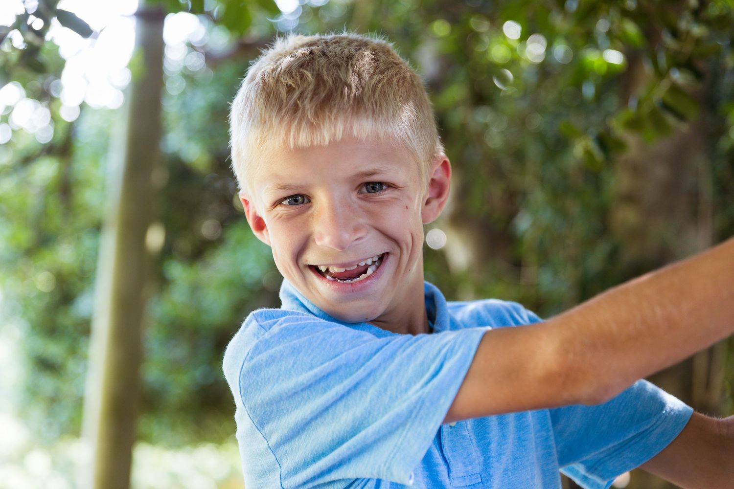 Child playing outdoors in natural lighting among trees.