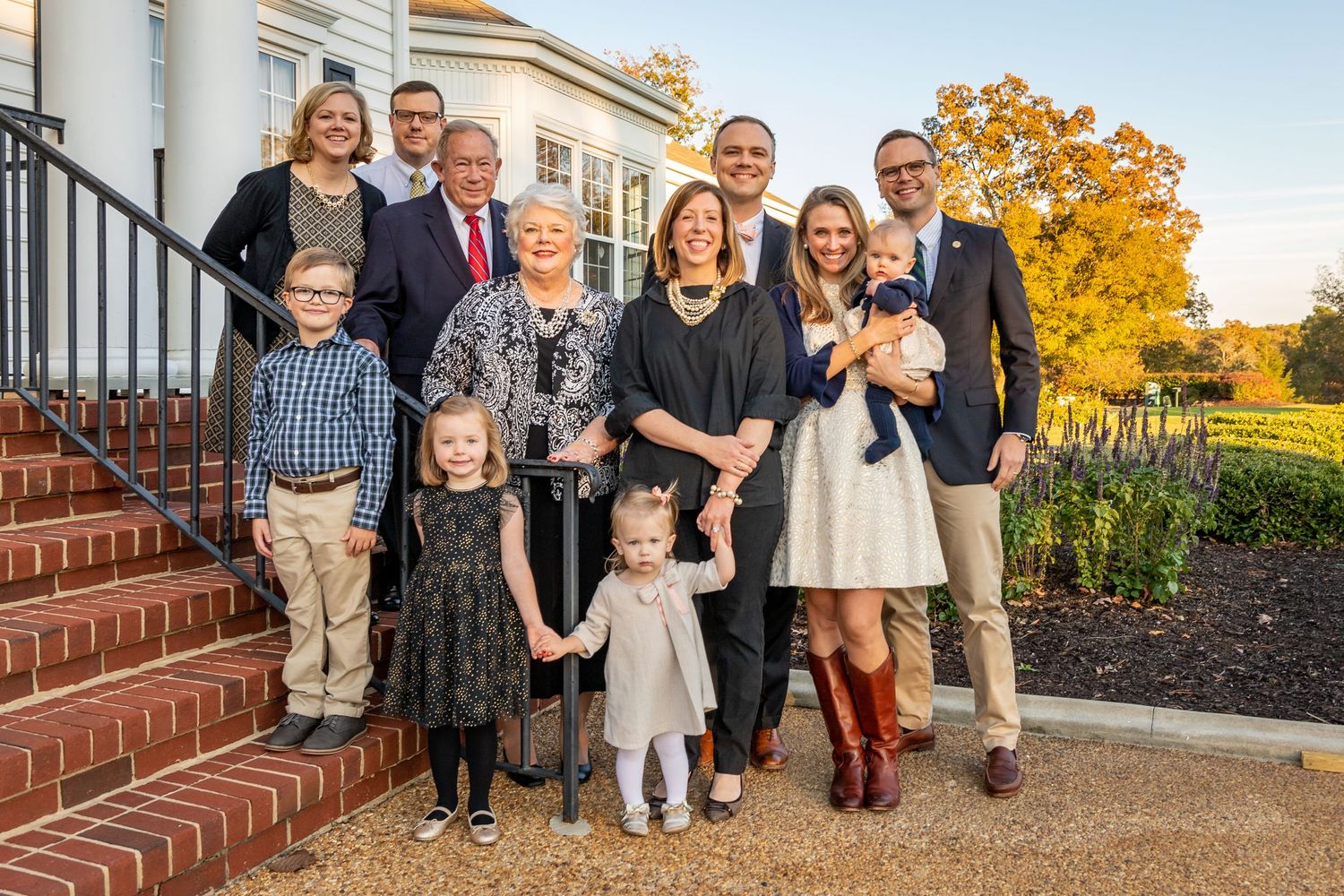 Family portrait session outdoors during golden hour with brick steps and autumn foliage.