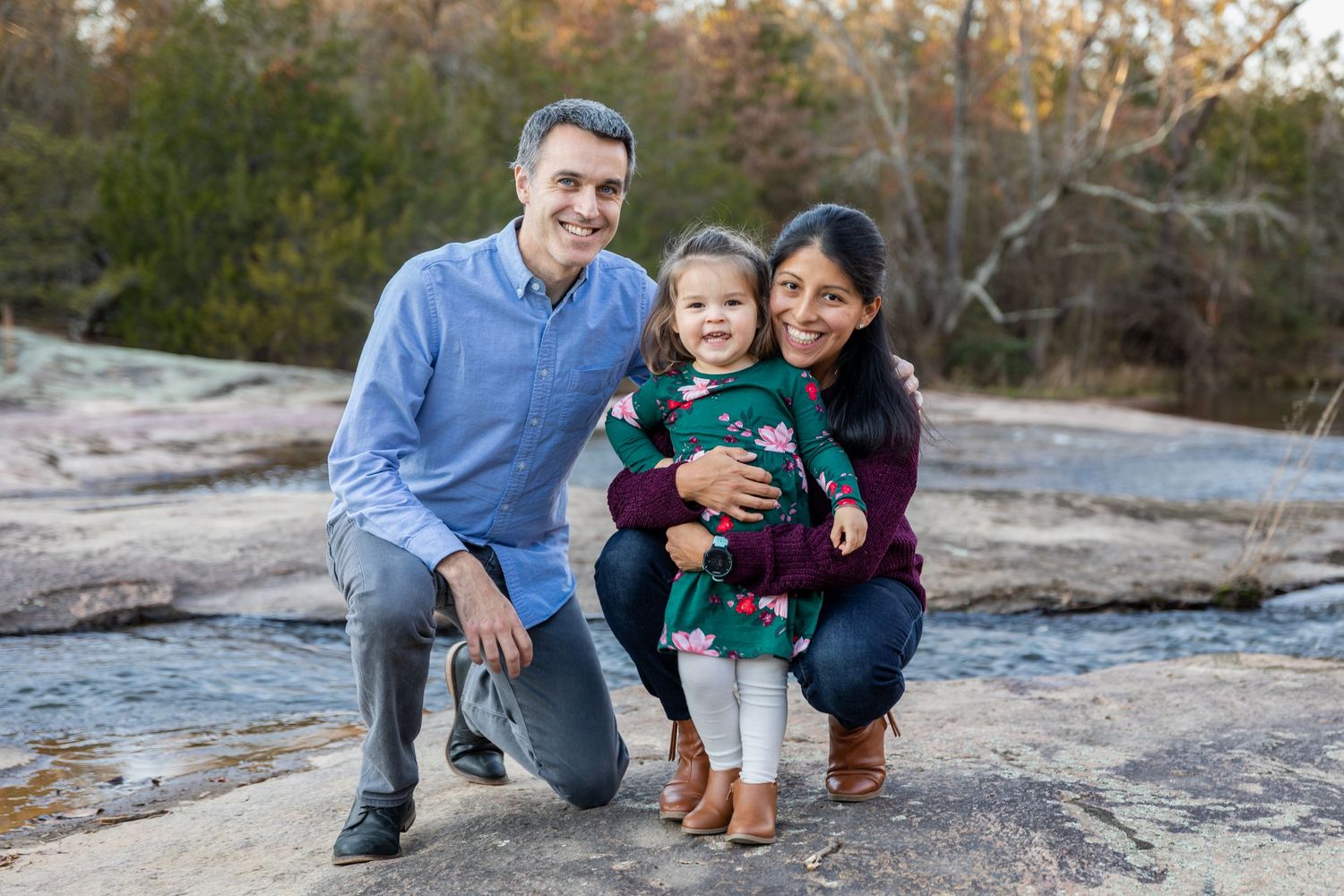 Family enjoying autumn weather while posing together on rocky terrain during an outdoor photo session.