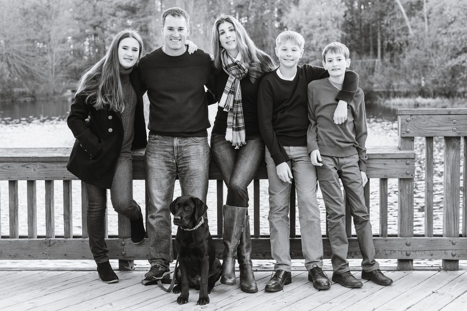 A black and white group portrait taken outdoors on a wooden deck.