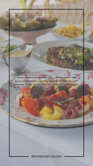 A colorful seasonal tomato dish with bright citrus and berries on an ornate plate.