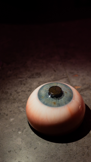 An artistic dessert designed to look like a realistic blue eye on a dark surface.