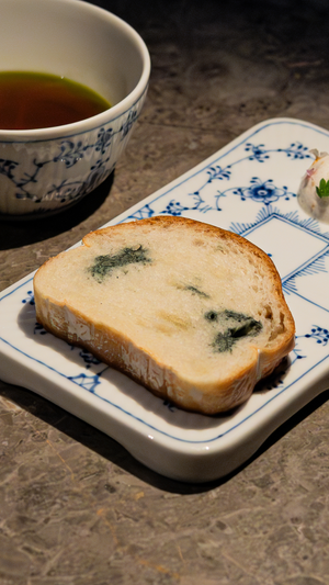 A slice of blue-speckled bread served on traditional blue and white porcelain with tea.