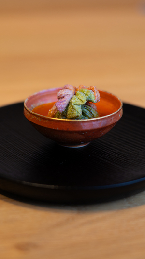 Vibrant rainbow-colored shrimp dish served in rustic ceramic bowl on black platter.
