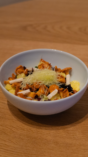 Asian-inspired dish with microgreens and golden mushrooms served in white ceramic bowl.