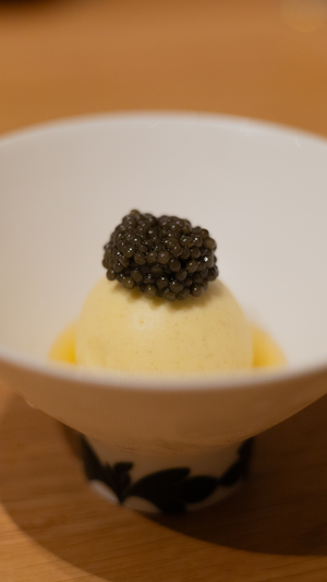 Gourmet caviar presentation on creamy base in white ceramic bowl with bat motif.