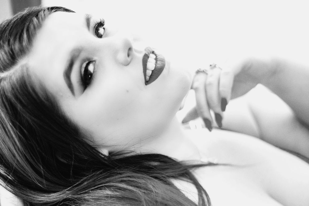Black and white close-up portrait with dramatic lighting and expressive pose.