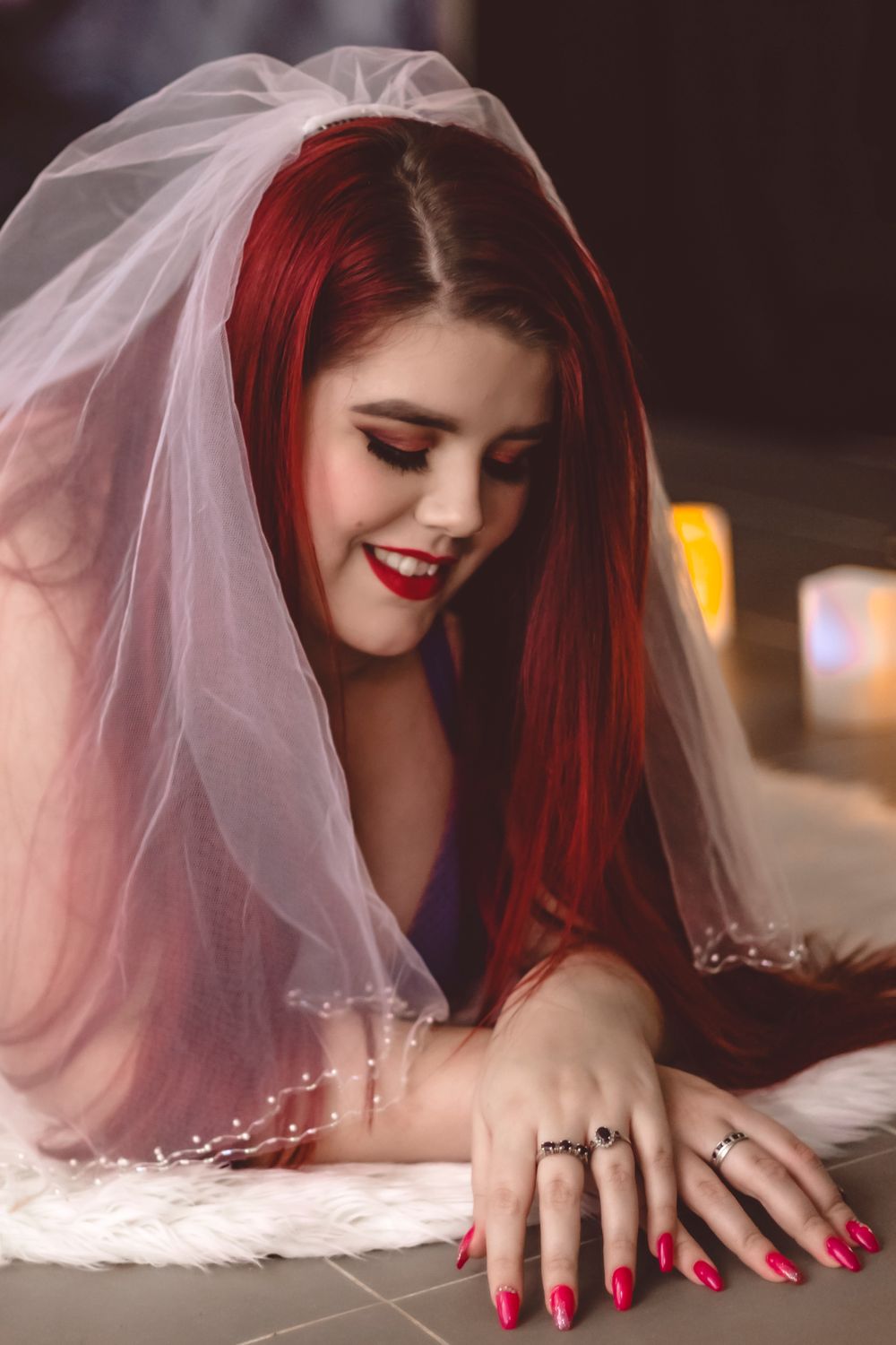 Bridal boudoir photo featuring white veil and romantic candlelit setting.