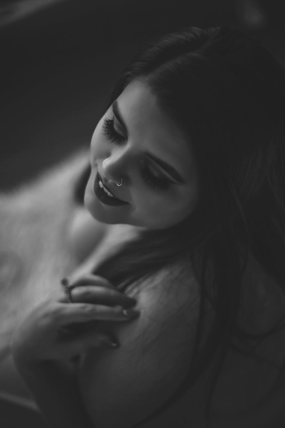 Dramatic black and white boudoir portrait with soft shadows and intimate pose.