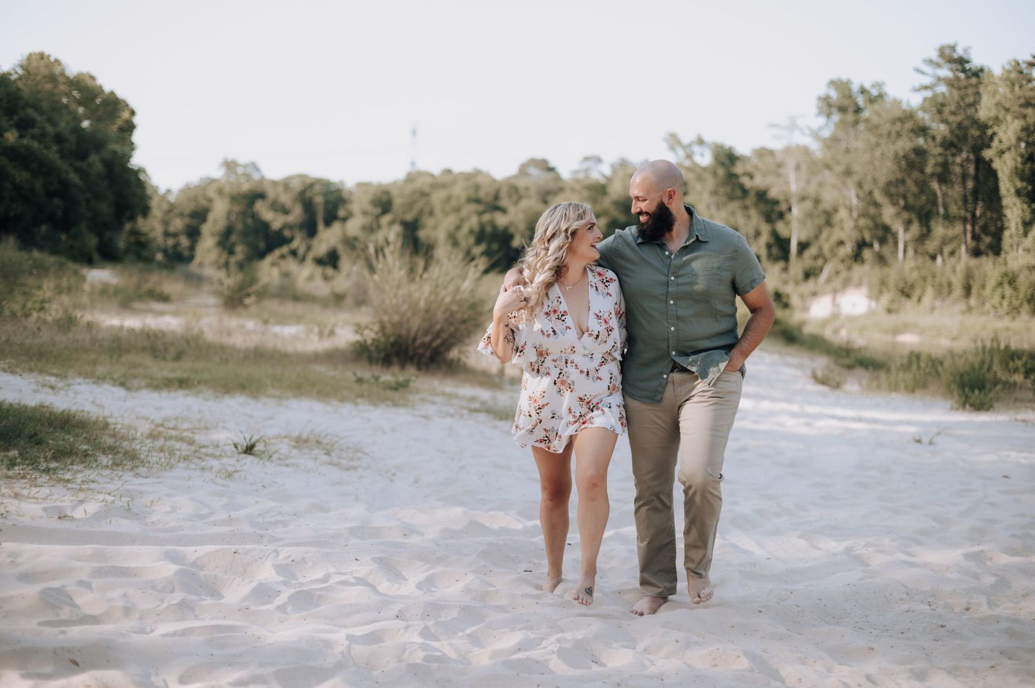 Couple walking together on sandy path surrounded by natural landscape.